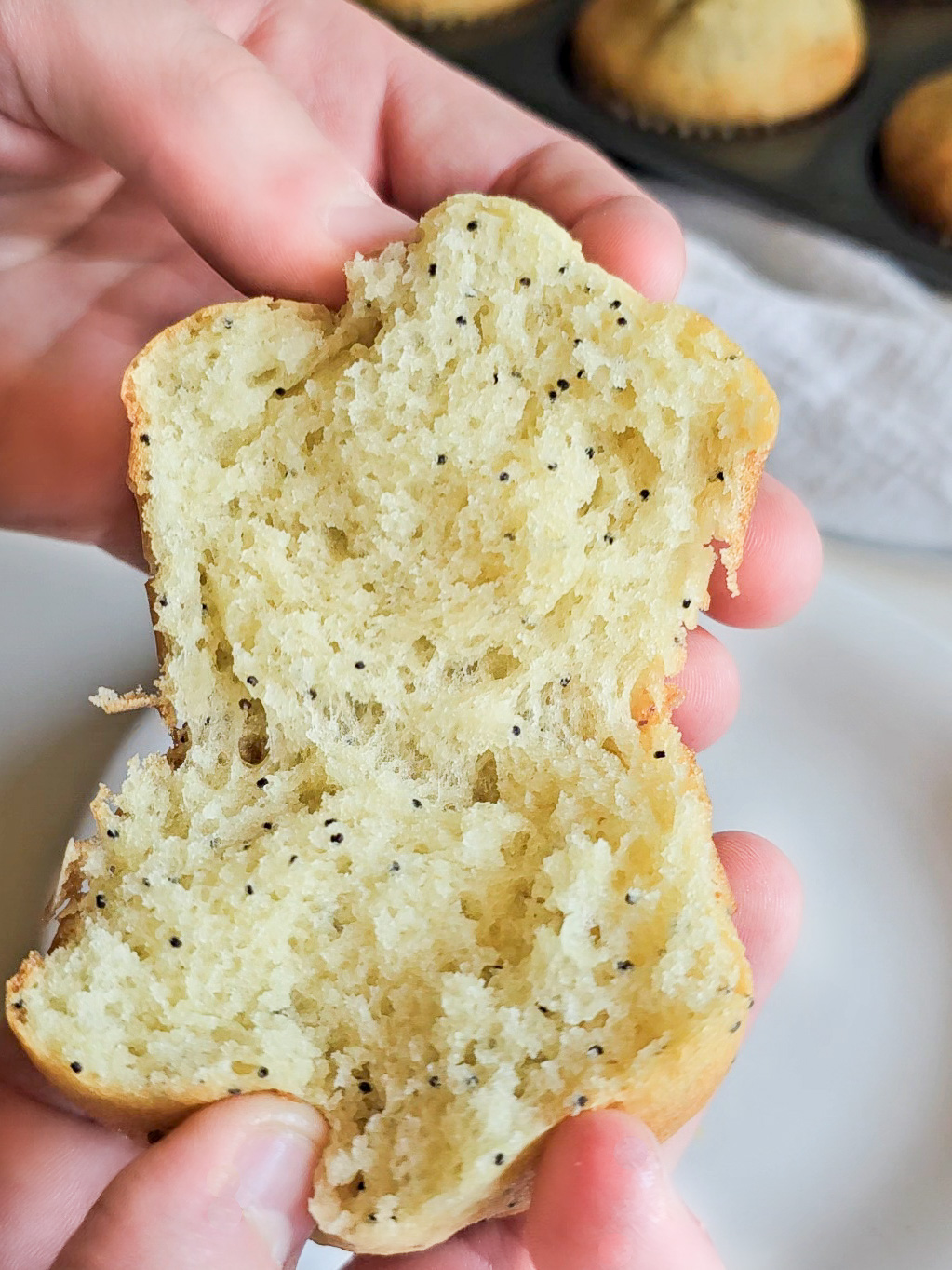 two hands tearing a soft muffin apart
