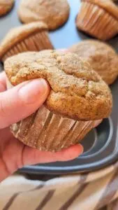 a hand gently squishes a gluten free bran muffin to show how soft it is.