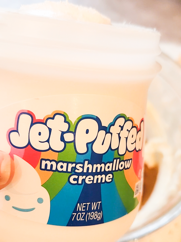 a hand holds a jar of Jet-Puffed marshmallow creme