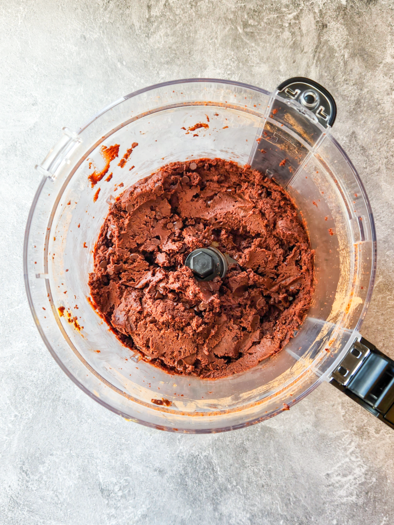 a food processor is filled with a fudgy brownie batter.