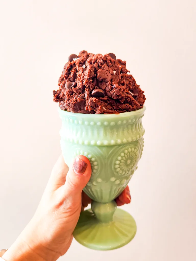 Brownie batter is piled high in a green blown glass sundae cup. 