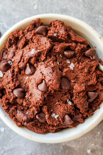 thick, dark brown batter in a bowl, topped with chocolate chips and flaky salt