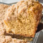 A serving spatula is lifting a slice of gluten free coffee cake out of the pan.