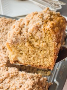 A serving spatula is lifting a slice of gluten free coffee cake out of the pan.