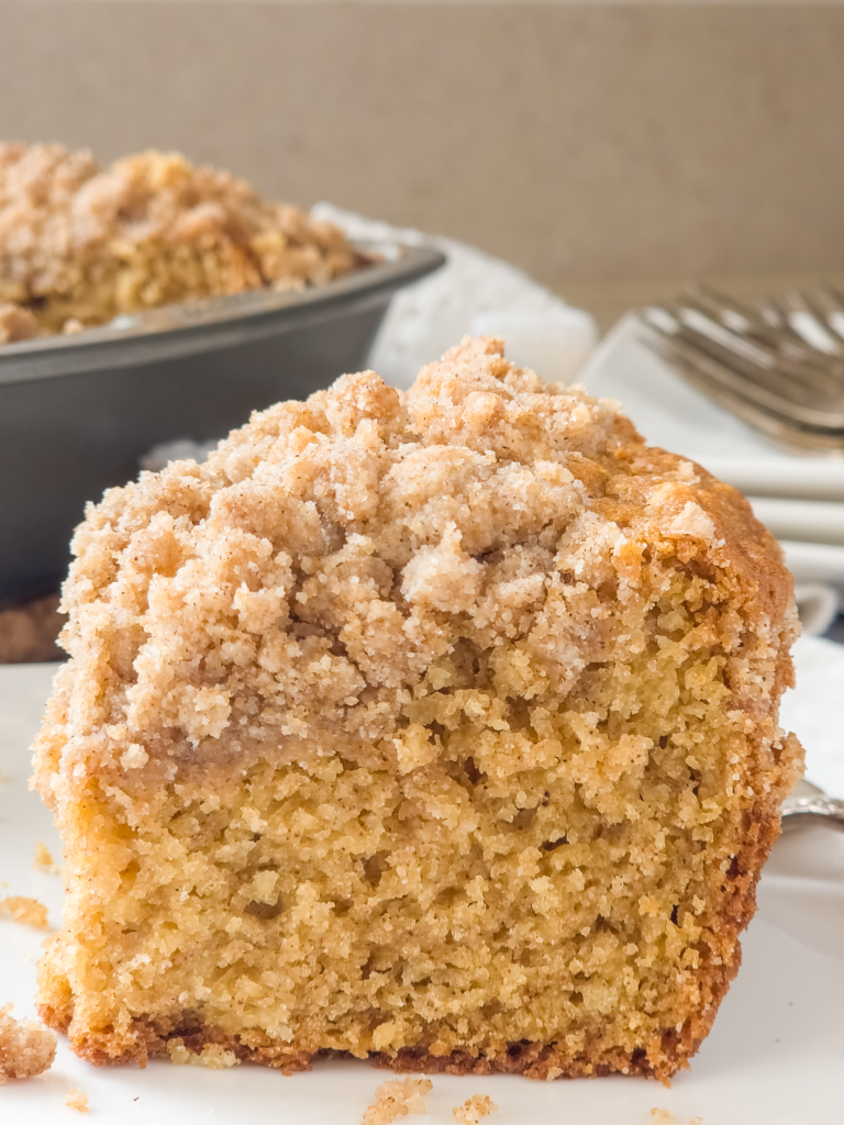 A slice of coffee cake with crumb topping on a plate.