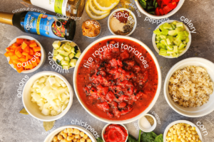 ingredients in Panera Bread 10 vegetable soup are laid out in bowls. Bowls are filled with: fire roasted tomatoes, celery, brown rice, corn, salt and pepper, tomato paste, chickpeas, onions, carrots, zucchini, coconut aminos, vinegar, garlic, lemon zest, spices, and peppers.