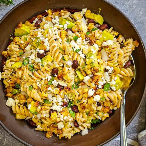 a bowl of gluten free mexican pasta salad in a brown ceramic bowl
