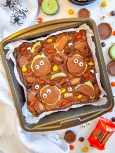 A pan of brownies topped with Reese's cups and googly eyes
