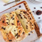 loaf of gluten free Irish soda bread, sliced on a wooden cutting board.