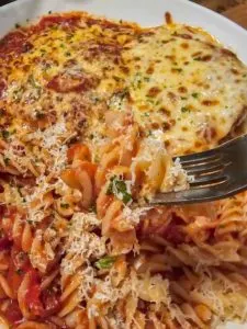 a plate of gluten free chicken parmesan with rotini and lots of cheese