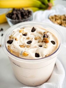 Ninja Creami pint container with creamy banana ice cream, walnut pieces, and dark chocolate chips