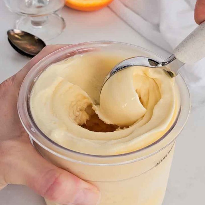 an ice cream scoop glides through orange ice cream