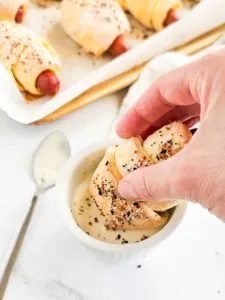 wrapped hot dog being dipped in sauce