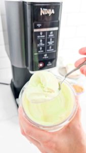 a spoonful of creamy ice cream with a Ninja Creami machine in back