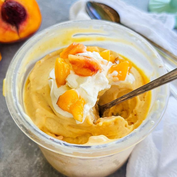 container of creamy peach ice cream with a spoon