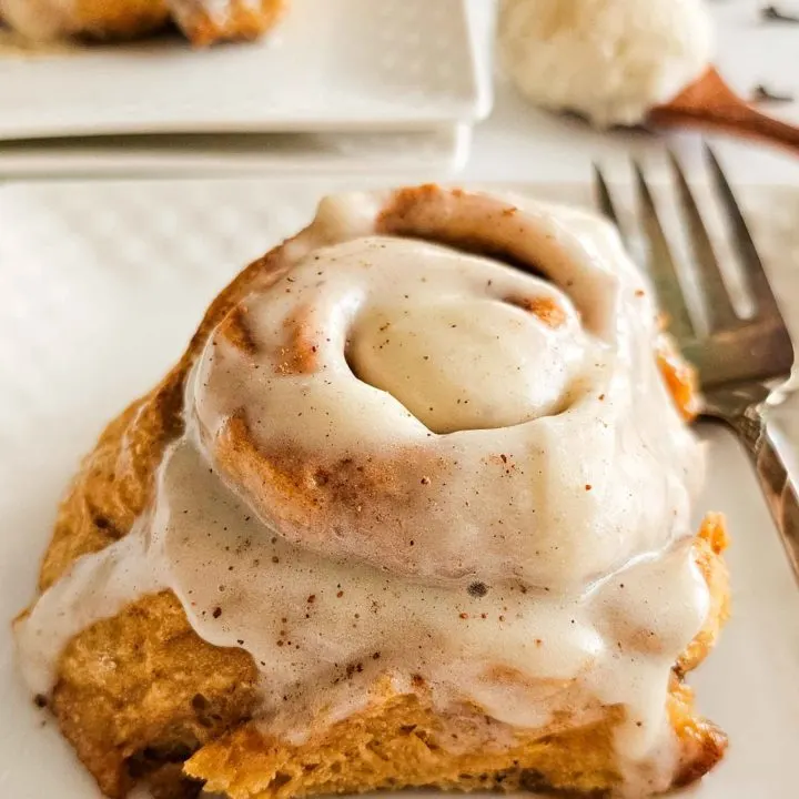 tall and gooey cinnamon roll on a plate