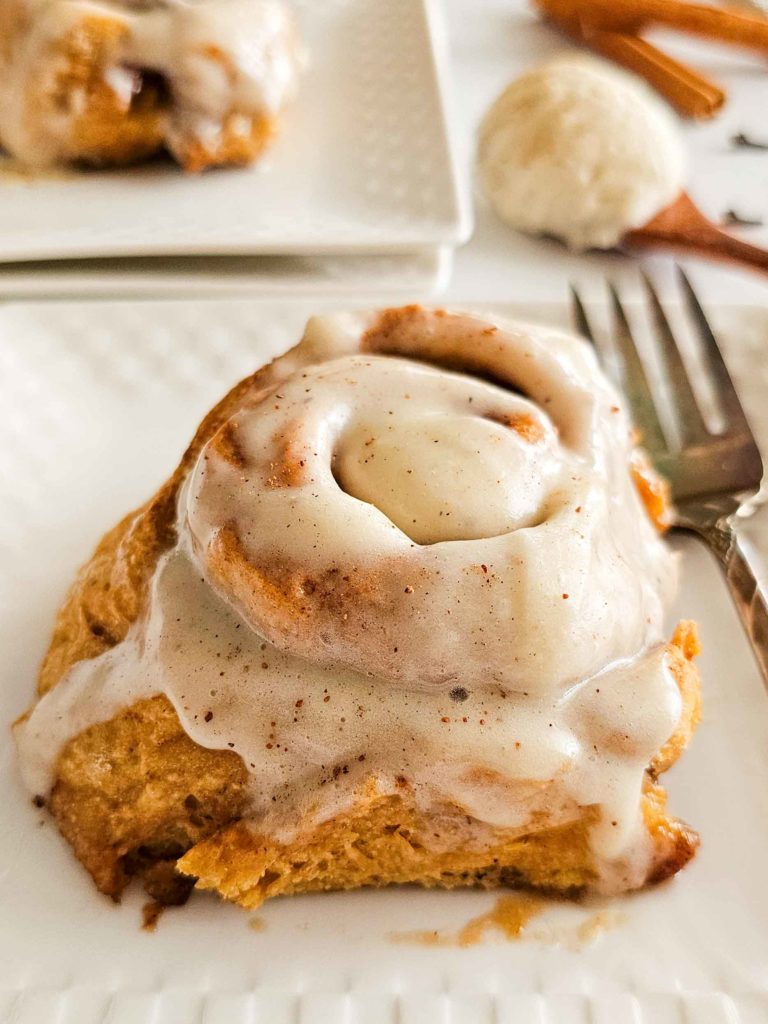 tall and gooey cinnamon roll on a plate