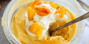 Creamy peach ice cream with whipped cream and chopped peaches on top